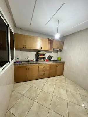 a kitchen with wooden cabinets and a tile floor at Beni mellal in Beni Mellal