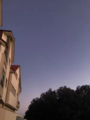 a clear blue sky above some buildings and trees at AM Atlas Home in Ifrane