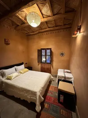 a bedroom with a bed and a table and a ceiling at Kasbah Ennakb in Nkob