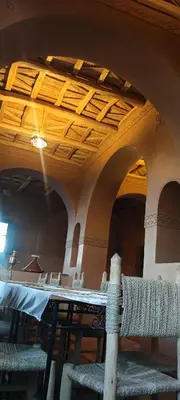 a dining room with a table and a ceiling at Kasbah Ennakb in Nkob