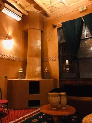 a living room with a table and a fireplace at Kasbah Ennakb in Nkob