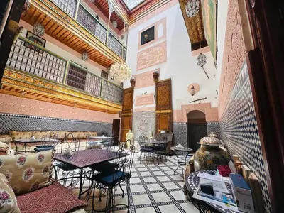 a room with tables and chairs in a building at Riad Dar Tahri & SPA in Fès