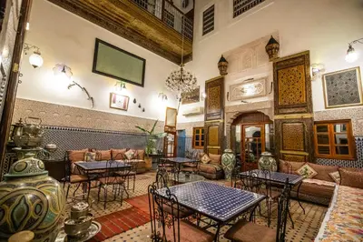 a room with tables and couches in a building at Riad Dar Tahri & SPA in Fès