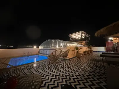 a swimming pool at night with chairs around it at Riad Dar Tahri & SPA in Fès