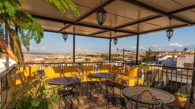 a balcony with tables and chairs and a view of a city at Riad Dar Tahri & SPA in Fès