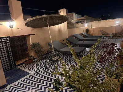 a patio with chairs and an umbrella and plants at Riad Dar Tahri & SPA in Fès