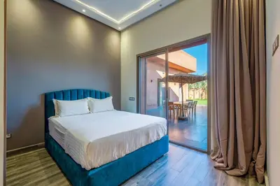 a bedroom with a bed and a sliding glass door at Villa de Luxe Ouidane 5 Chambres in Marrakech