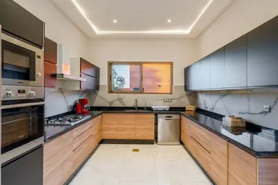 a large kitchen with wooden cabinets and black counter tops at Villa de Luxe Ouidane 5 Chambres in Marrakech