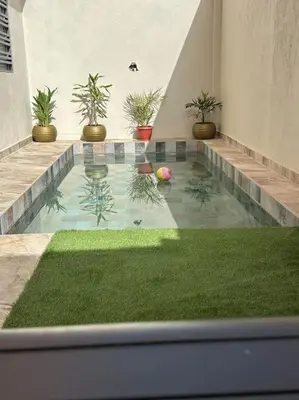 a swimming pool with grass and plants in a building at Appartement Cosy avec piscine à Khenifra in Khenifra