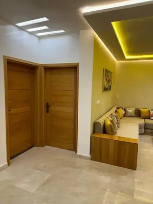 a living room with a couch and two wooden doors at Appartement Cosy avec piscine à Khenifra in Khenifra