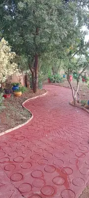 a red brick walk way with trees in the background at Jamarou in Marrakech