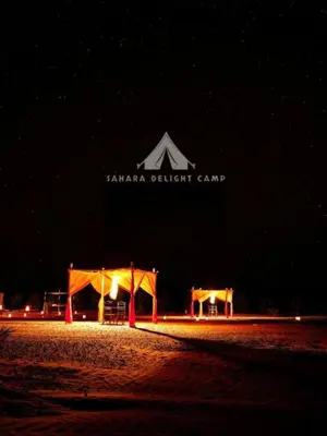 a tent and a pavilion on the beach at night at Sahara Delight Camp in Merzouga