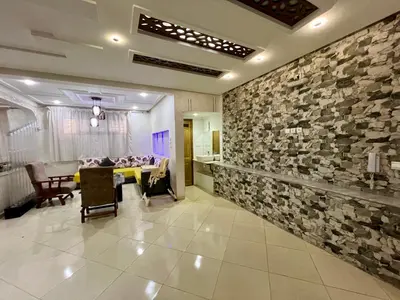 a living room with a stone wall and a table at Dar Fes Medina - Guest Rooms in Fès