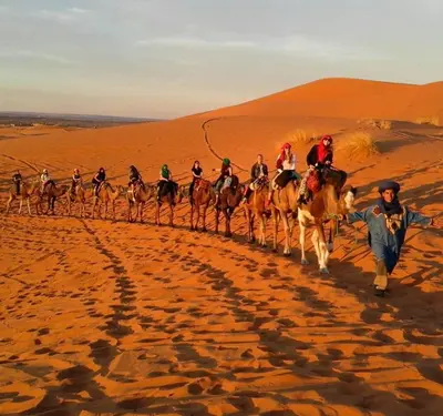 a group of people riding horses in the desert at Adrar desert camp in Merzouga
