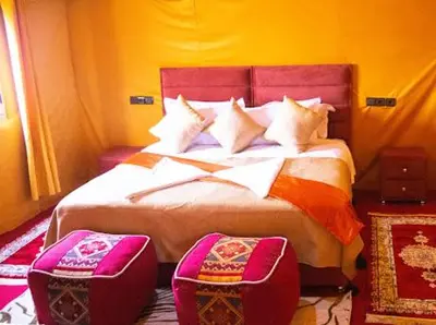 a bedroom with a large bed with two chairs at Andromeda Desert Astro Camp in Derkaoua