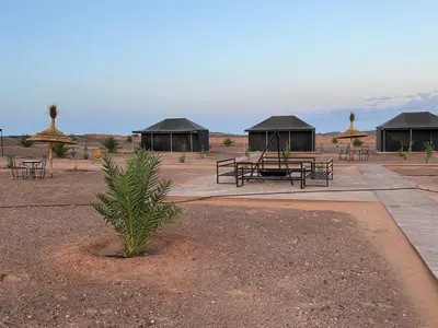 a group of picnic tables and gazebos in the desert at Andromeda Desert Astro Camp in Derkaoua