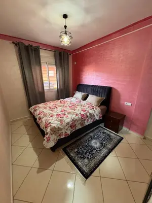 a bedroom with a bed and a red wall at appartement a jawharat atlass 2 in Beni Mellal