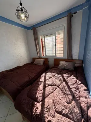 a bedroom with two beds and a window at appartement a jawharat atlass 2 in Beni Mellal