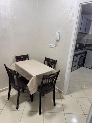 a dining room table with two chairs and a kitchen at appartement a jawharat atlass 2 in Beni Mellal