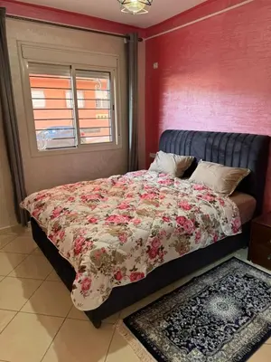 a bed with a floral comforter in a bedroom at appartement a jawharat atlass 2 in Beni Mellal