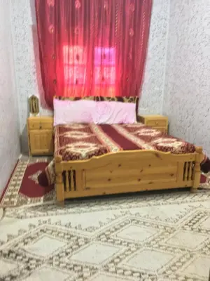 a bedroom with a wooden bed with a red curtain at Ounilla valley in Tizgui nʼBarda