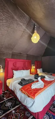 a bedroom with a red bed with clothes on it at Mountain luxury camps in Merzouga