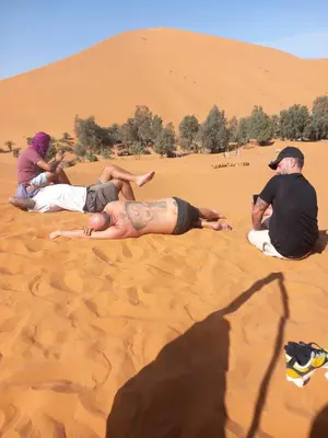 a group of people laying in the sand in the desert at merzouga desert camp in Merzouga