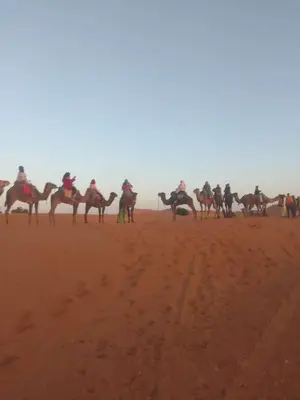 a group of people riding horses in the desert at merzouga desert camp in Merzouga