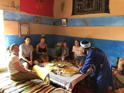 a group of people sitting around a table at merzouga desert camp in Merzouga