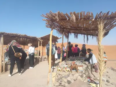 a group of people standing around a table in the desert at merzouga desert camp in Merzouga