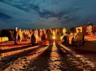 a group of people standing around in the desert at night at merzouga desert camp in Merzouga