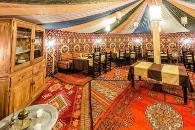 a dining room with tables and chairs in a building at merzouga desert camp in Merzouga