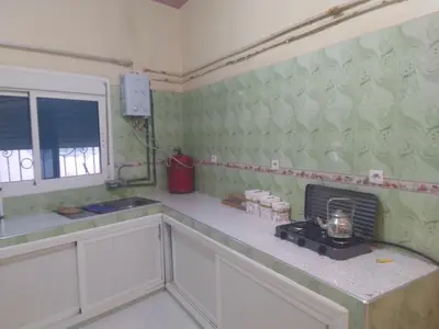 a kitchen with white cabinets and green wallpaper at شقة للكراء اليومي بمركز تنغير in Tinerhir