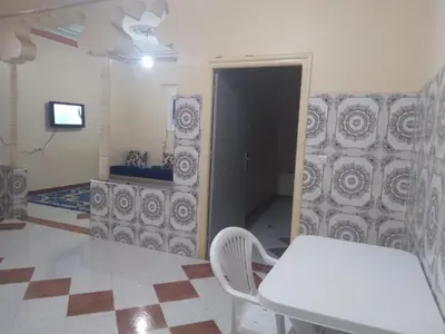 a room with a table and a door with a television at شقة للكراء اليومي بمركز تنغير in Tinerhir