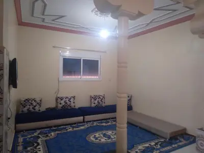 a living room with a blue couch and a window at شقة للكراء اليومي بمركز تنغير in Tinerhir
