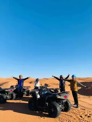 a group of people standing in the desert with their atvs at Desert Nights Camp in Merzouga
