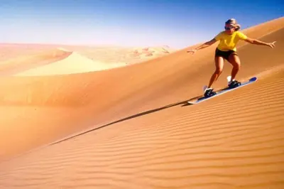 a woman riding on top of a sand dune in the desert at Desert Nights Camp in Merzouga