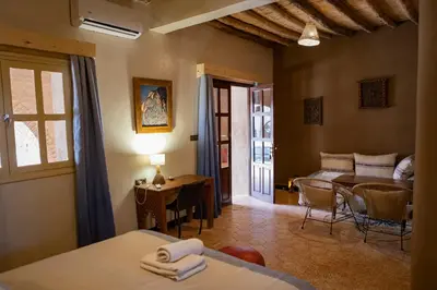 a bedroom with a bed and a dining room with a table at Ksar Sania - Merzouga in Merzouga