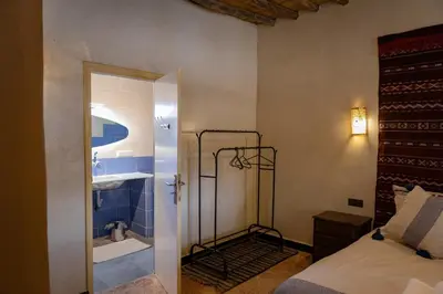 a bedroom with a bed and a bathroom at Ksar Sania - Merzouga in Merzouga