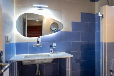 a blue tiled bathroom with a sink and a mirror at Ksar Sania - Merzouga in Merzouga