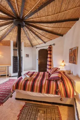 a bedroom with a large bed with a wooden ceiling at Ksar Sania - Merzouga in Merzouga