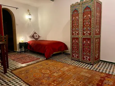 a bedroom with a red bed and a large cabinet at Rooms in Dar Drouj, a special 14th century house Riad in Fès
