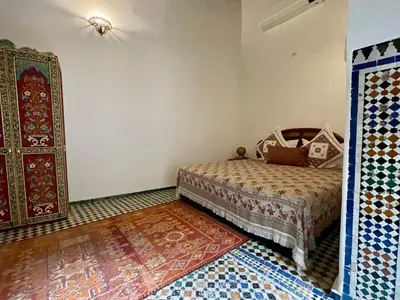 a bedroom with a bed and a rug in a room at Rooms in Dar Drouj, a special 14th century house Riad in Fès