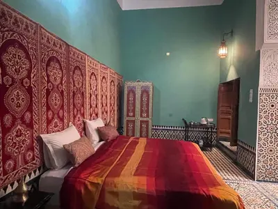 a bedroom with a bed with a colorful blanket at Rooms in Dar Drouj, a special 14th century house Riad in Fès