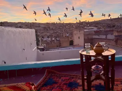 a group of birds flying over a city with a table at Rooms in Dar Drouj, a special 14th century house Riad in Fès