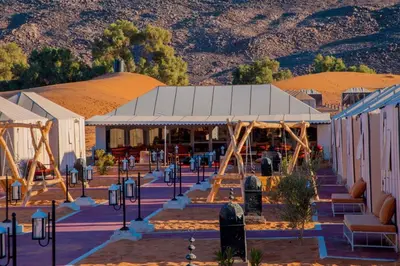 a building in the desert with mountains in the background at Sahara Desert Camp in Merzouga