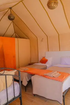 a room with three beds in a tent at Sahara Desert Camp in Merzouga