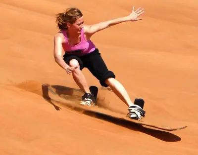 a woman riding a skateboard in the sand at Sahara Desert Camp in Merzouga