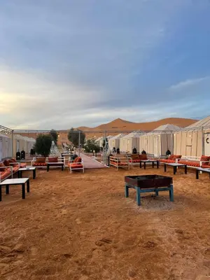 a group of benches in a field with tents at Sahara Desert Camp in Merzouga