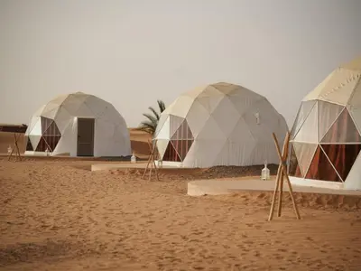 three domes in the desert on a sandy field at Sahara Bubble in Merzouga